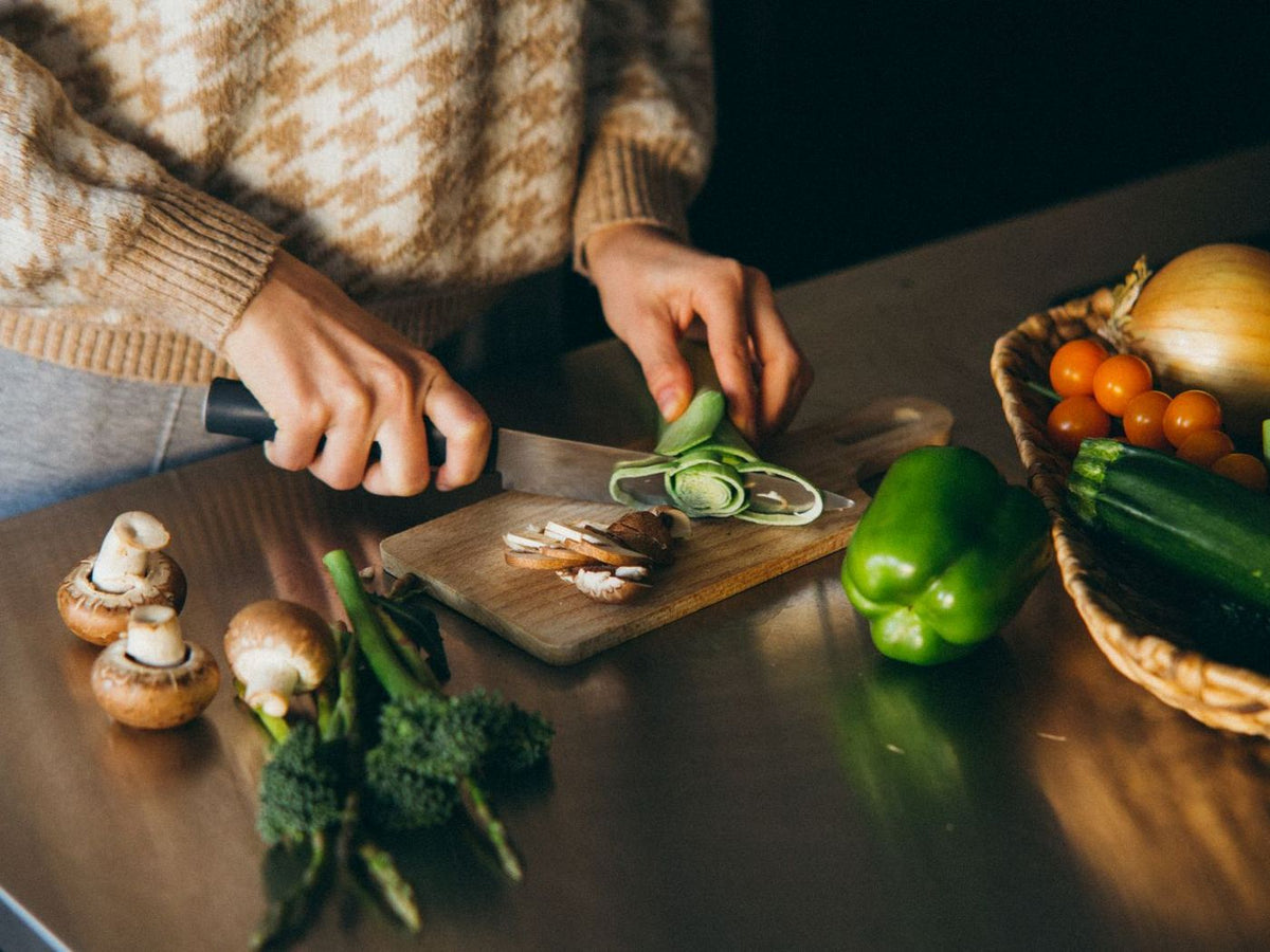 Hands slicing fresh vegetables on a wooden board